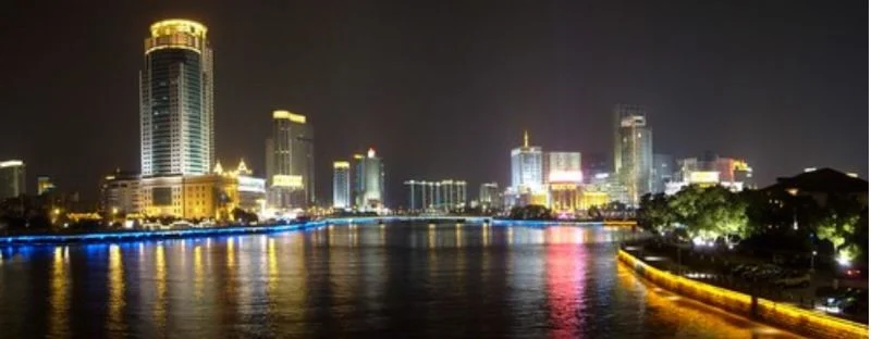 City skyline and river at night with lit towers reflected in the water
