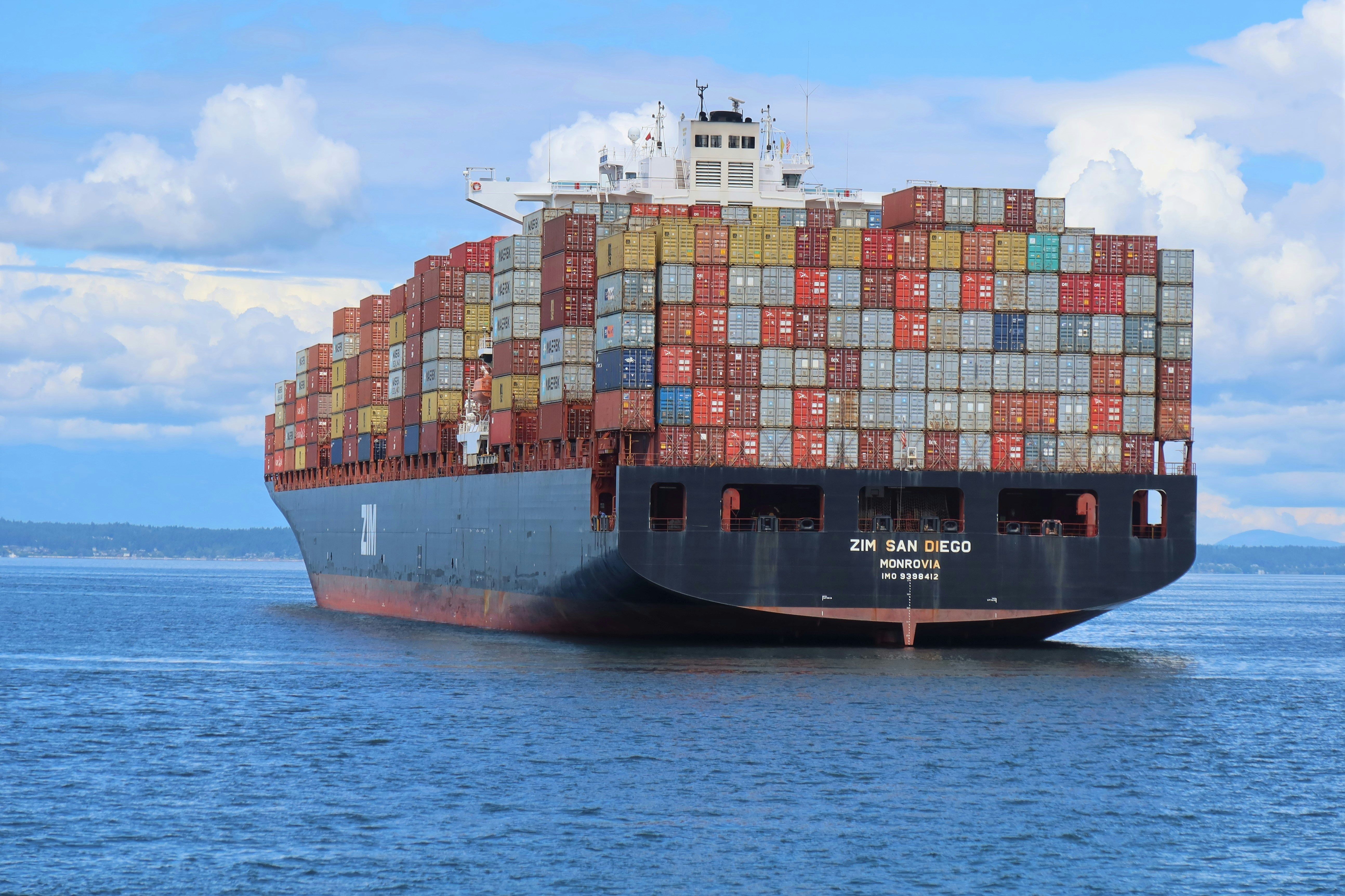 Container ship loaded with stacked containers sailing on open water