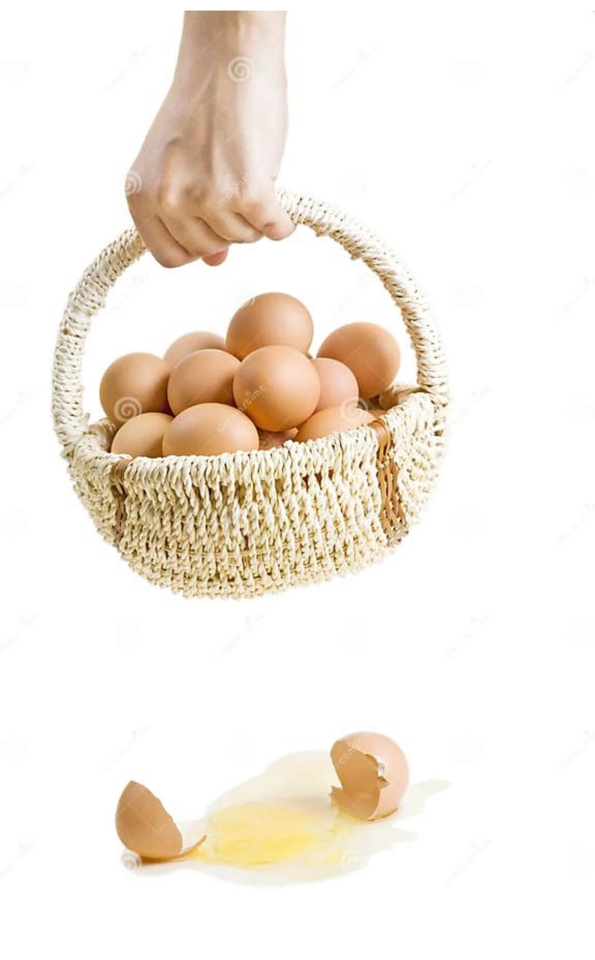 Hand holding a woven basket of brown eggs above a single cracked egg on the ground