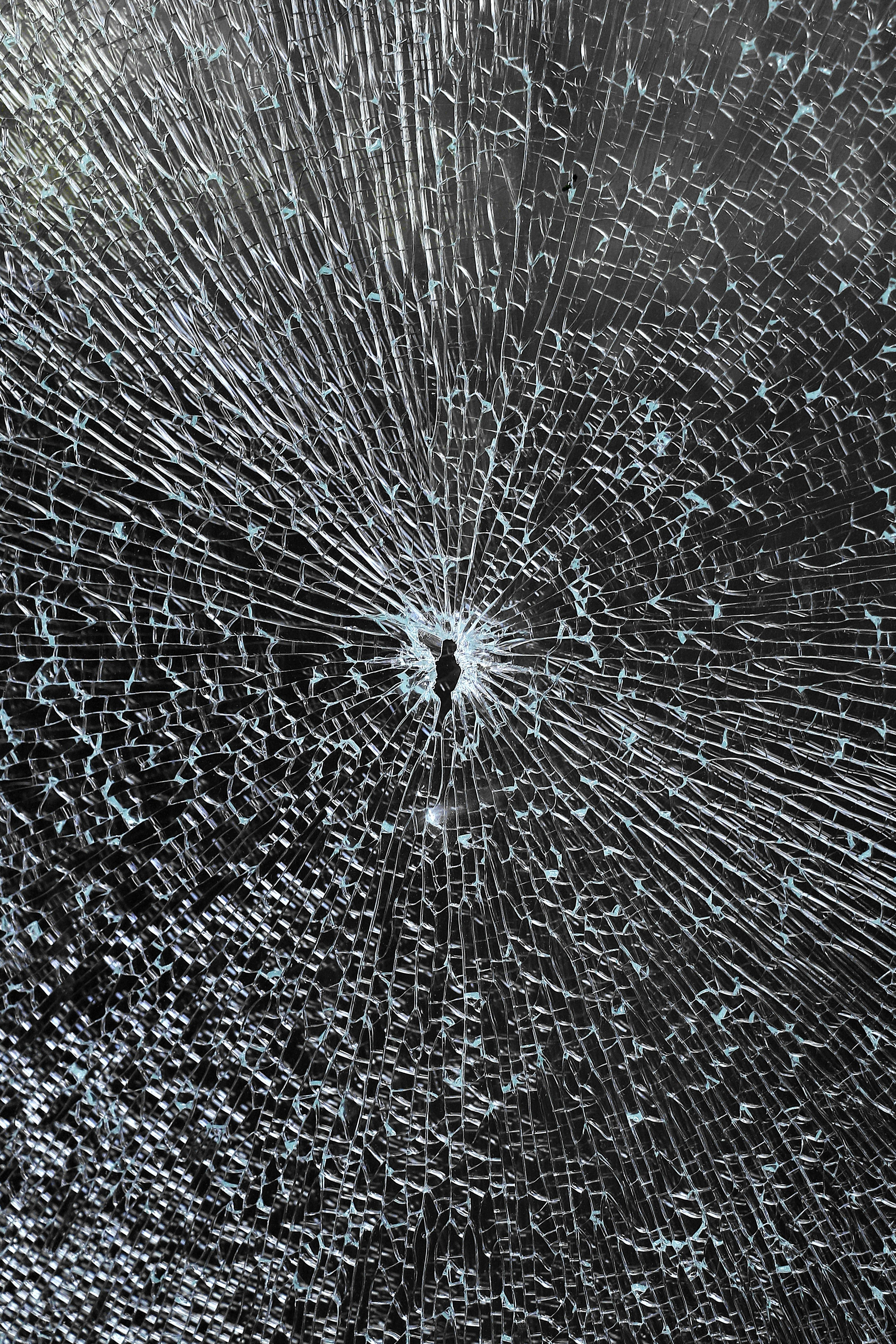 Shattered glass with cracks radiating from a small hole in the centre